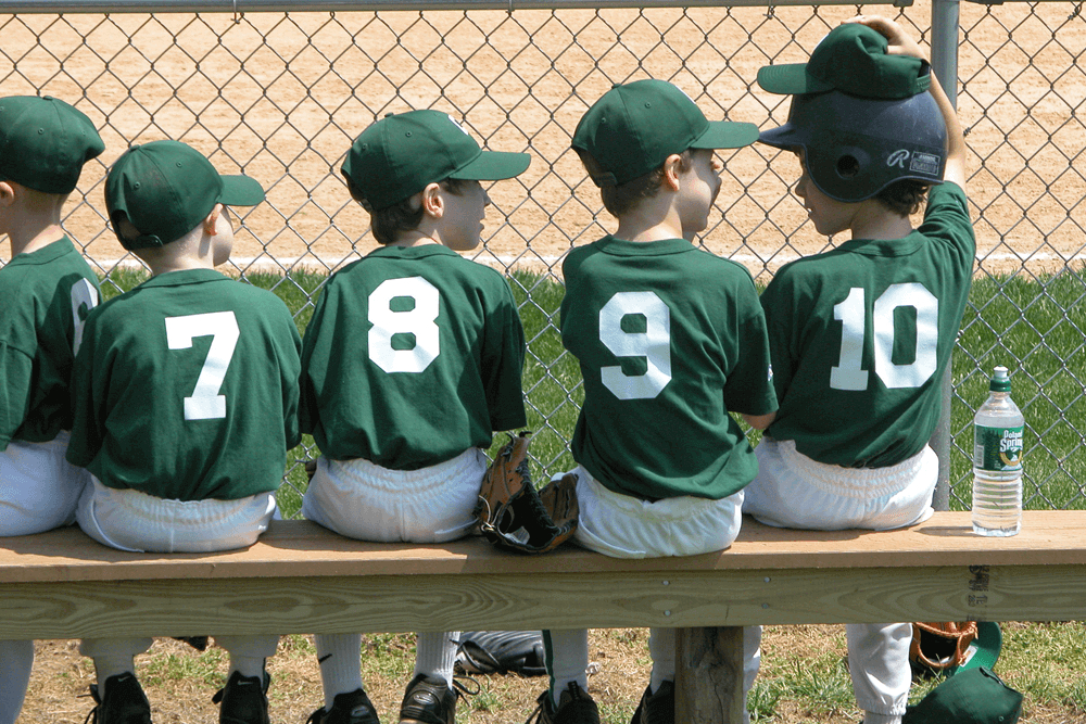 Rear view little league baseball team sitting on bench