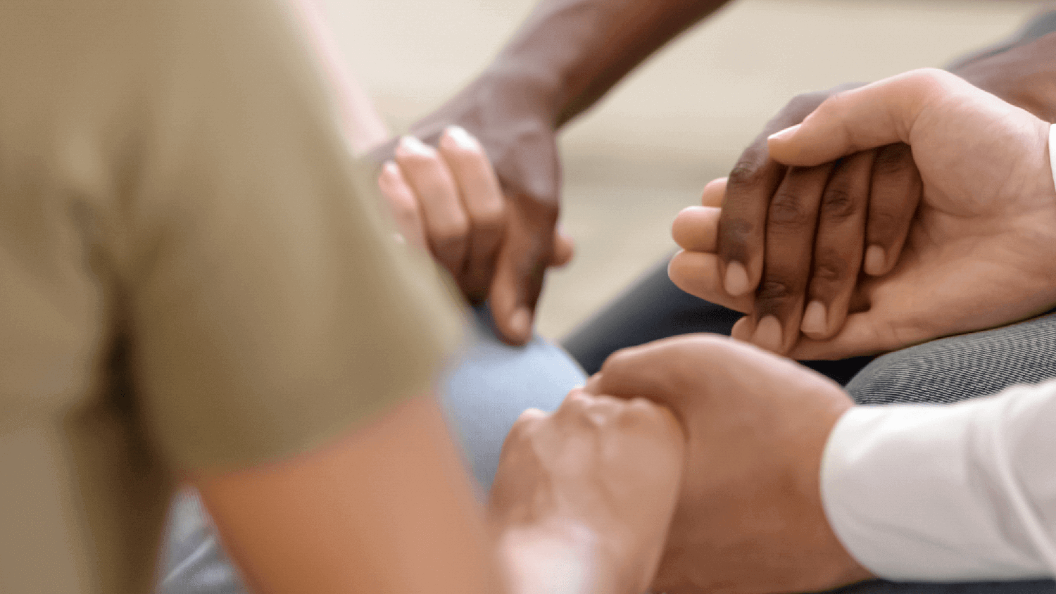 close up image of people holding each others hands and praying together